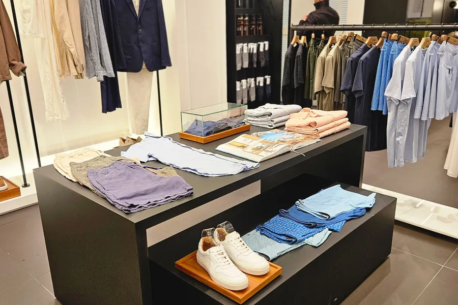 A retail store interior with painted walls, clothing rails and a central display table.