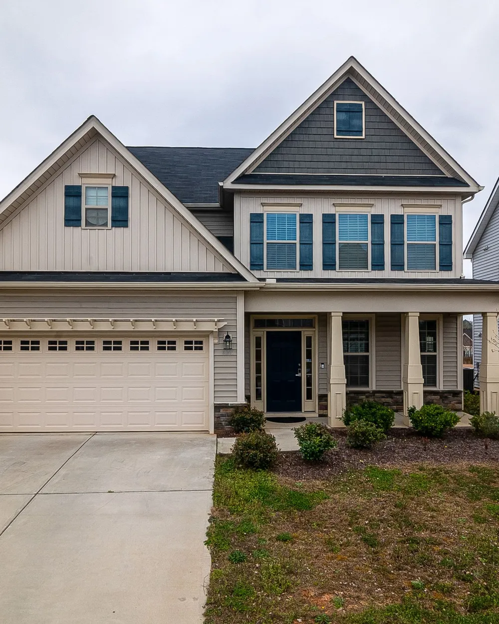 A two-story suburban home with freshly painted siding, white trim, shutters and a two-car garage door.