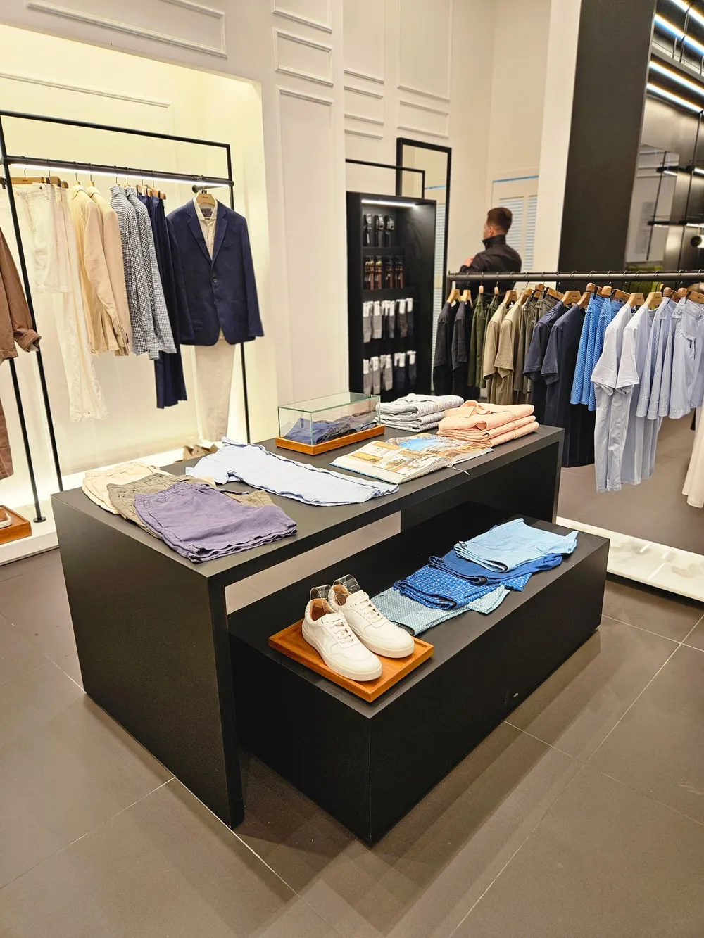 A retail store interior with painted walls and ceiling, clothing rails, mirrors and a central display table.