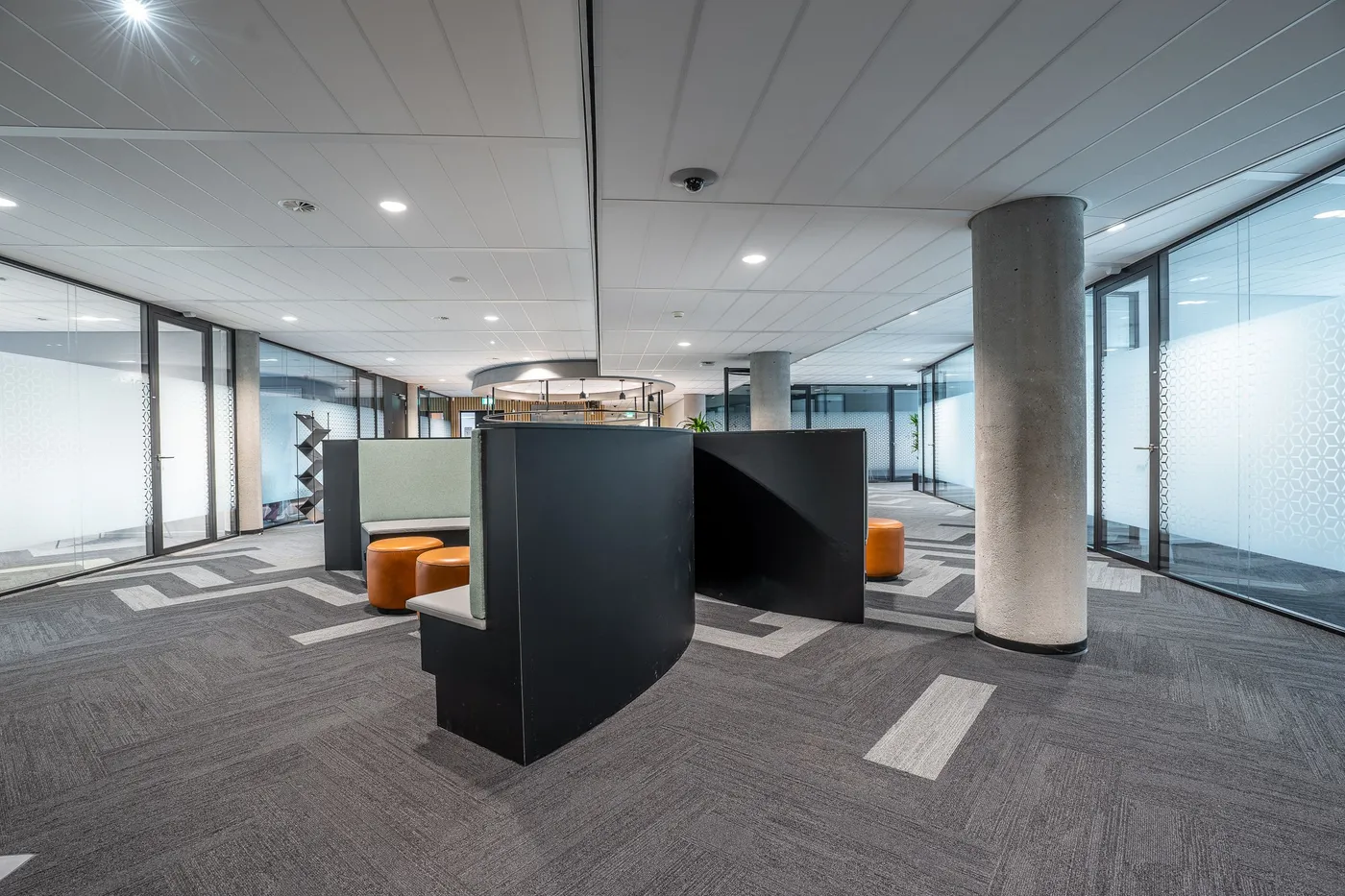 An empty open-plan office with painted walls and ceiling, a structural column and dark partition units.